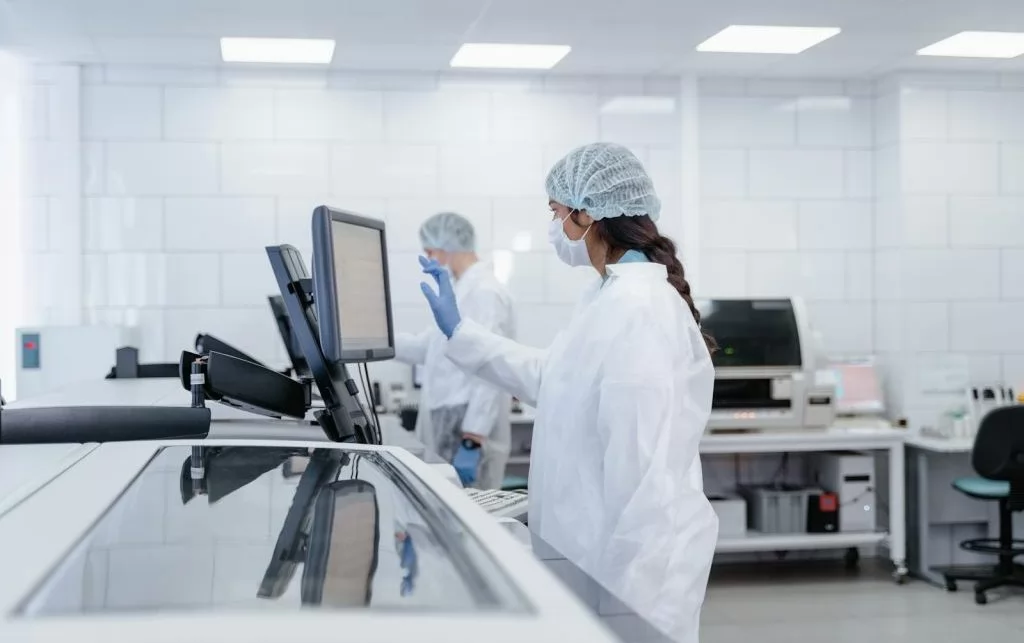 Scientist in protective gear operates equipment in a modern lab.