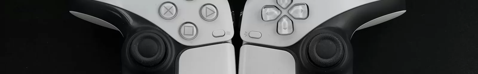 Top-down view of two modern white gaming controllers on a black surface.