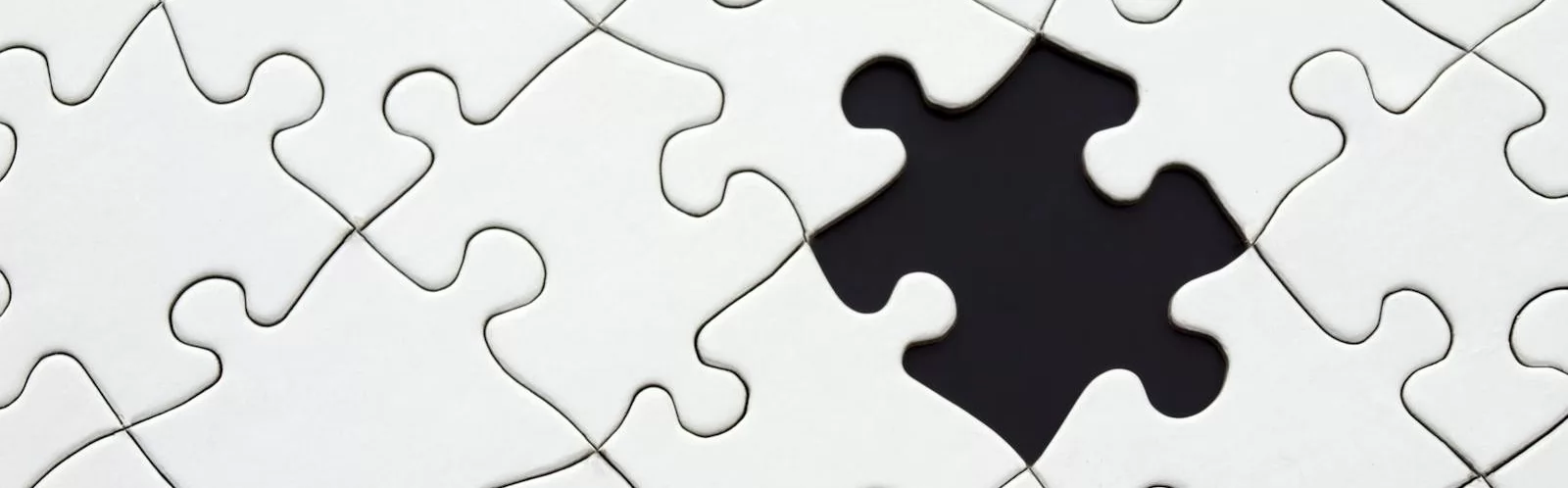 Close-up of an incomplete white puzzle with one missing piece, symbolizing challenge and strategy.