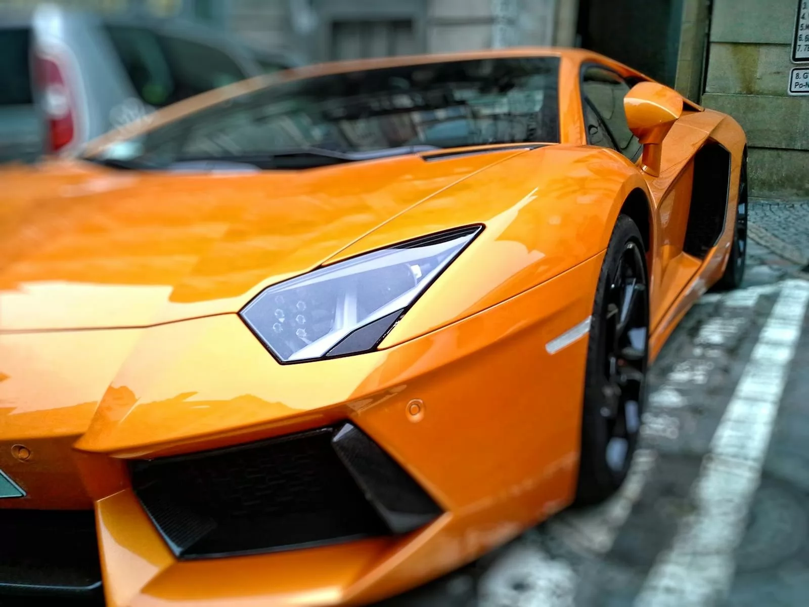 A striking orange luxury sports car parked on a city street in Brno, Czechia.