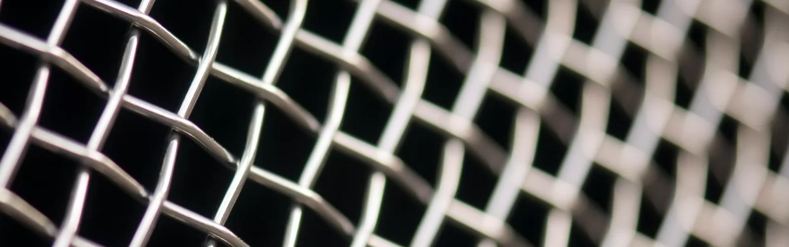 Detailed close-up of metal wire mesh pattern with a blurred background, showcasing texture and structure.